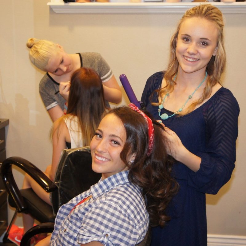 Loyal customer and hairstylist curling and fixing hair at The Forum Academy.